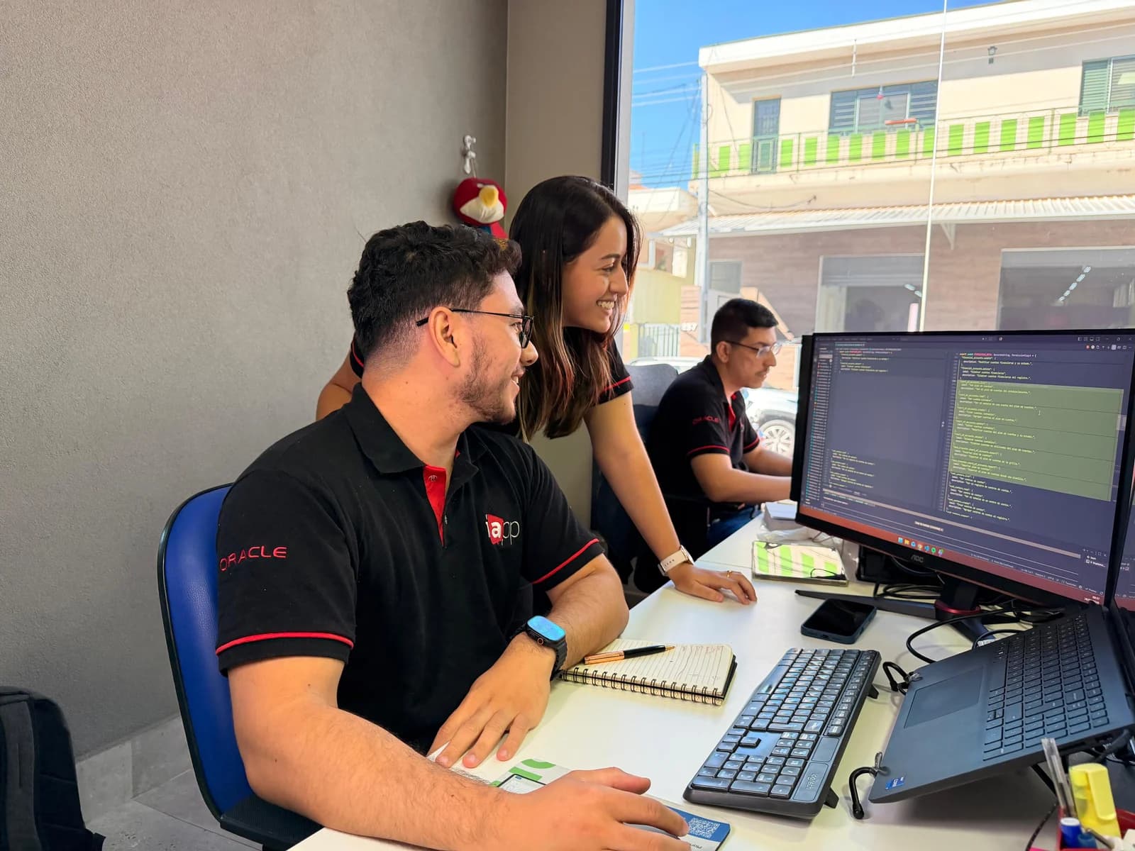 Time de desenvolvimento acompanhando código em um monitor na sede